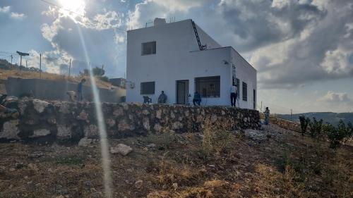 un bâtiment blanc sur le côté d'une colline dans l'établissement الاردن جرش سوف المناره بالقرب من لواء قصبة جرش شاليه الكوت الاردني, à Khirbat Ra”s al Madīnah