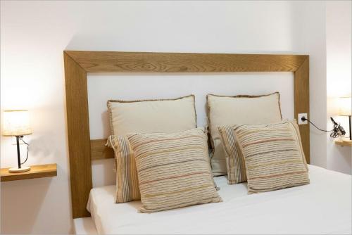 a bed with a wooden headboard with two pillows at Ziv Boutique Apartments Town Square II in Lefkada Town