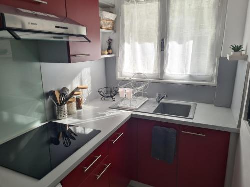 d'une cuisine avec des placards rouges, un évier et une fenêtre. dans l'établissement Appartement Mediterranée 150m de la Plage, à Canet