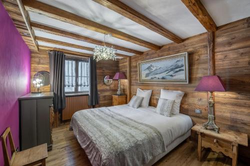 a bedroom with a bed in a room with wooden walls at Chalet Lièvre Blanc - LES CHALETS COVAREL in Val-d'Isère