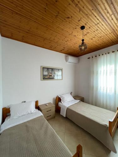 two beds in a bedroom with a wooden ceiling at Rent Rooms Sakolli in Berat