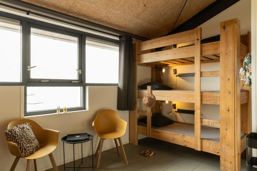 a room with bunk beds and a desk and chairs at Brouwersdam Stay in Ouddorp