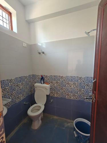 a bathroom with a toilet and blue and white tiles at Rahgir Guest House in Almora