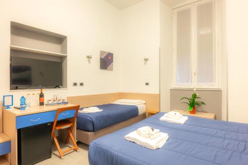 a room with two beds and a desk and a tv at Affittacamere del Golfo e delle 5 Terre in La Spezia