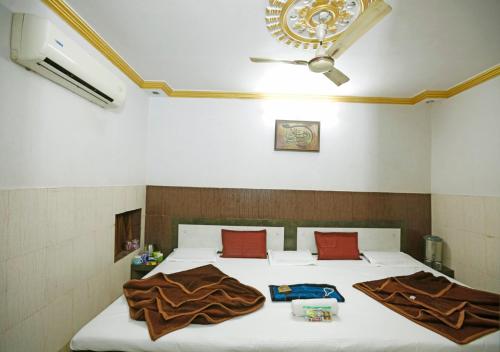 a bedroom with a bed with white sheets and red pillows at Hotel Gulshan E Razia Manzil in Ajmer