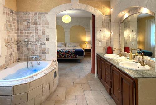 een badkamer met 2 wastafels en een bad met een bed bij Yaor Shiatsu Yoga soins, stages, retraites avec jacuzzy in Ladern-sur-Lauquet
