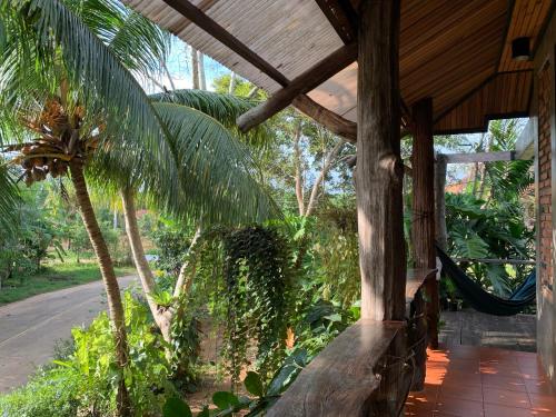 a porch of a house with a hammock on it at Wooden House,Rustic charm in quiet area in Ban Khlong Chi Lat