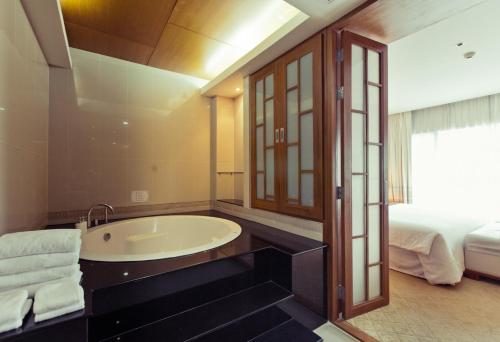 a bathroom with a bath tub and a bed at Sunee Grand Hotel and Convention Center in Ubon Ratchathani