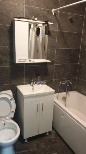 a bathroom with a toilet and a sink and a tub at White Apartments in Prishtinë