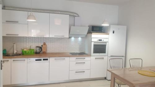 a white kitchen with white cabinets and a table at White Apartments in Prishtinë