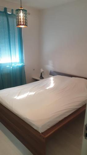 1 cama en un dormitorio con cortina azul y lámpara de araña en White Apartments, en Pristina