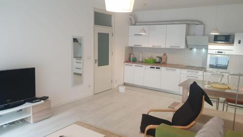 a kitchen with white cabinets and a living room at White Apartments in Prishtinë