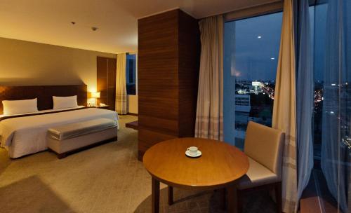 a hotel room with a bed and a table and a window at Sunee Grand Hotel and Convention Center in Ubon Ratchathani