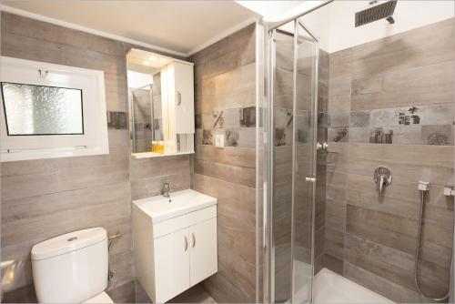a bathroom with a toilet and a glass shower at Ziv Boutique Apartments Town Square II in Lefkada Town