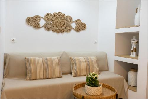 a couch with two pillows and a clock on the wall at Ziv Boutique Apartments Town Square II in Lefkada Town