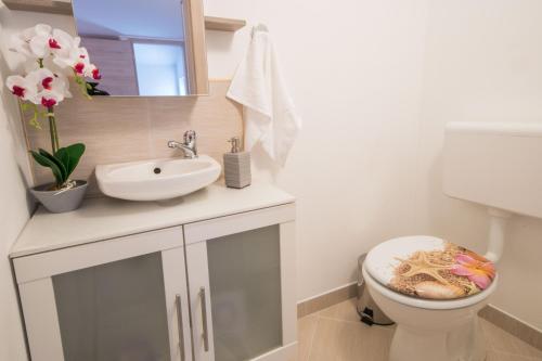 a white bathroom with a sink and a toilet at Villa Veronika, a cozy and charming Villa for Summer holidays in Lakošelci