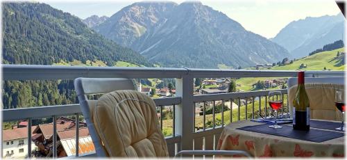 a balcony with a table and two glasses of wine at Ferienwohnung Vier Jahreszeiten in Hirschegg