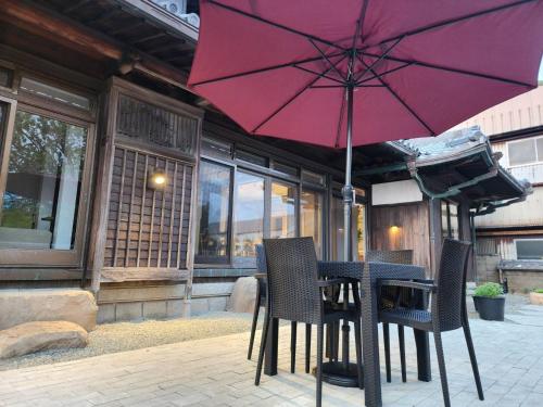 una mesa y sillas con una sombrilla roja en el patio en Tiz庵　善 en Minato