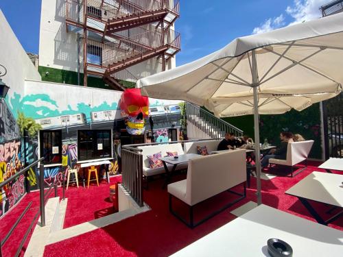 un patio con tavoli, sedie e ombrellone di We Street Hostel - El Arenal-Albergue juvenil a El Arenal