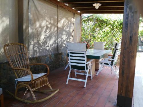 una veranda riparata con sedie e tavolo di Villa al mare Baia Emiri Mazzaforno Cefalù a Cefalù