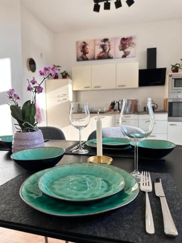 une table avec des assiettes vertes et des verres à vin dessus dans l'établissement City Altstadt Appartement in unmittelbarer Nähe zu Saale und Marktplatz mit privatem Parkplatz, à Halle-sur-Saale