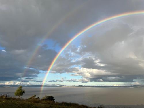a rainbow in the sky over a body of water at VistaMirage - Mystic Ridge Estate in Bywong
