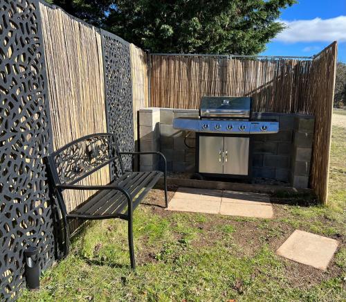 a grill and a bench next to a fence at VistaMirage - Mystic Ridge Estate in Bywong
