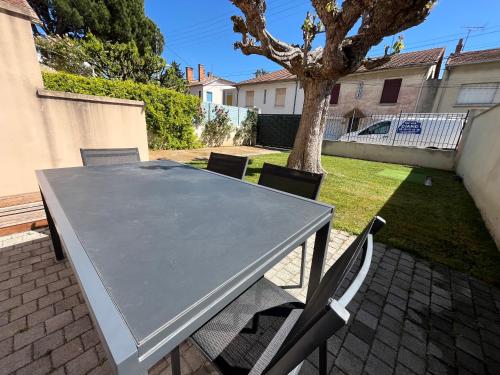 a gray table and chairs in a backyard with a tree at Maison familiale 3 chambres, parking gratuit in Avignon