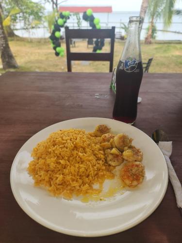 un plato de arroz frito y una botella de refresco en Tres Monos Hotel, Restaurante, Piscina, Bar, en Limones