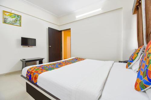 a bedroom with a bed and a tv on the wall at FabExpress Yashraj Inn - BJS College in Wagholi