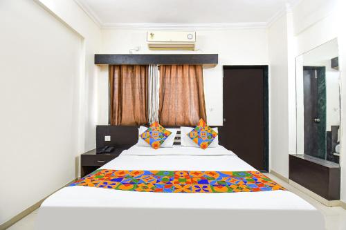 a bedroom with a large bed with colorful pillows at FabHotel Yashraj Inn in Vagholi