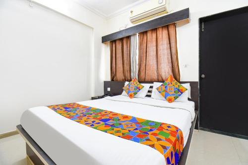 - une chambre avec un grand lit et une couverture colorée dans l'établissement FabHotel Yashraj Inn, à Vagholi