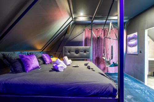 um quarto com uma cama grande e almofadas roxas em LoverDose by Les Gîtes du Moul1 em Duppigheim