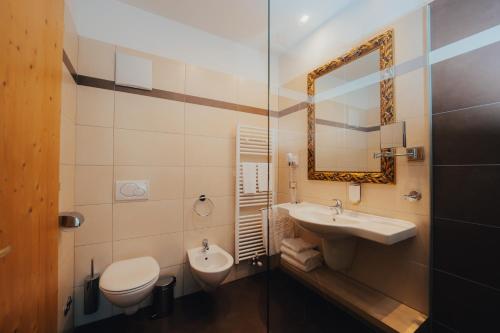 a bathroom with a sink and a toilet and a mirror at Parc Hotel Du Lac in Levico Terme