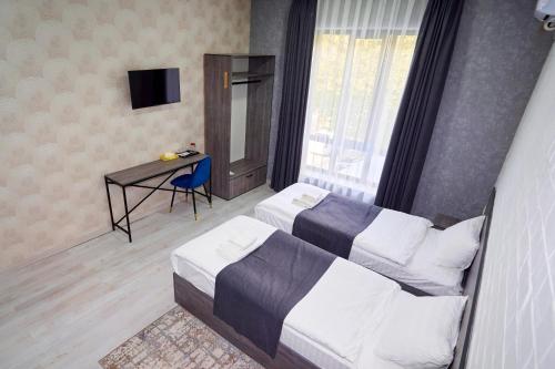 - une chambre avec 2 lits, un bureau et une télévision dans l'établissement Minguzar Hotel, à Tachkent