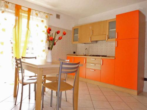 een keuken met oranje kasten en een tafel en stoelen bij Agritur Laura in Nago-Torbole