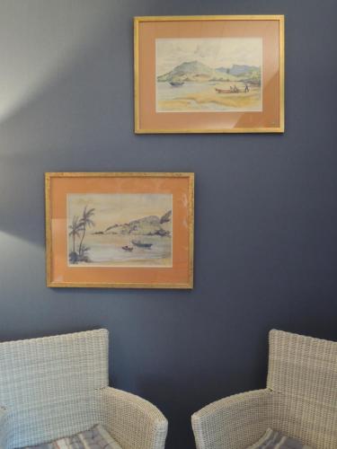 two pictures on a blue wall with two chairs at Via Bahia - Maison d'hôtes in Biscarrosse