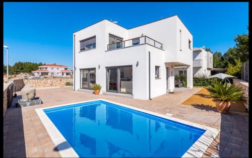 een wit huis met een zwembad ervoor bij Villa Tara in Srima