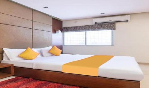 ein Schlafzimmer mit einem Bett mit gelben Kissen und einem Fenster in der Unterkunft FabExpress The Kings 10 Laxurious in Bangalore