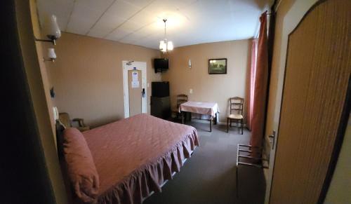 een slaapkamer met een bed en een tafel en stoelen bij Le Grand Connétable in Châteauneuf-de-Randon