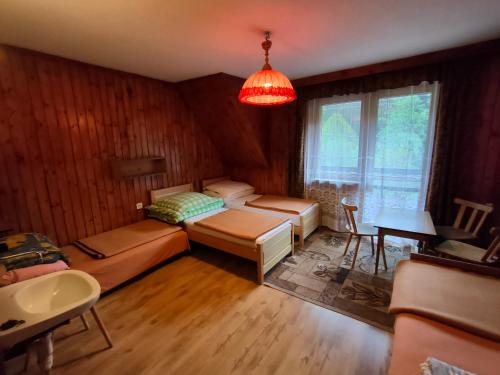 a room with two beds and a table and a window at Chata Pod Kwiatkiem in Zawoja
