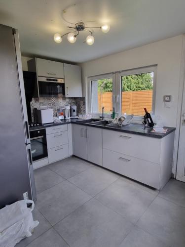 a kitchen with white cabinets and a counter top at Chez IZZA Chambre au calme in Poulainville