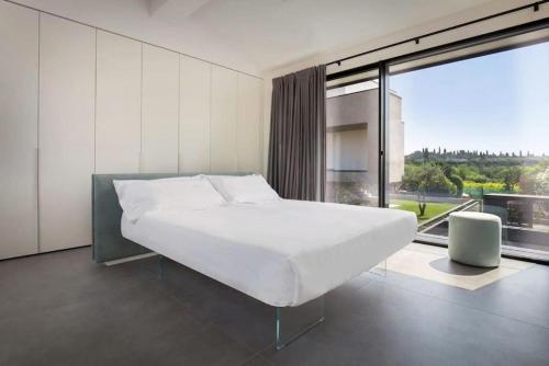 sypialnia z dużym białym łóżkiem i dużym oknem w obiekcie Villa Greghe-Lusso con piscina w mieście Lazise