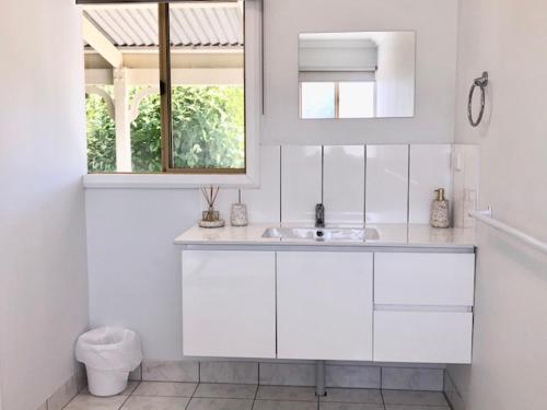 een witte badkamer met een wastafel en een raam bij MULBERRY LODGE in Woodridge