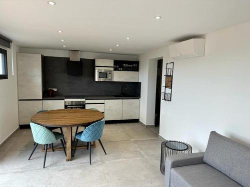 une cuisine et une salle à manger avec une table et des chaises en bois dans l'établissement Cosy Appartement Sari Solenzara, Jacuzzi, à Sari-Solenzara