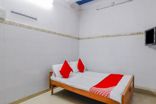 1 dormitorio con 1 cama con almohadas rojas y blancas en OYO 79037 Metro Lodge en Hyderabad
