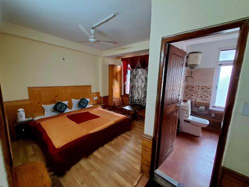 a bedroom with a large bed and a bathroom at Hotel Snow Mountain Mall Road in Manāli