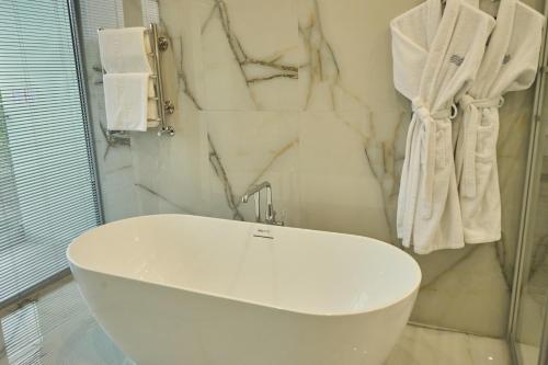 a white sink in a bathroom with marble walls at Almaty Hotel in Almaty