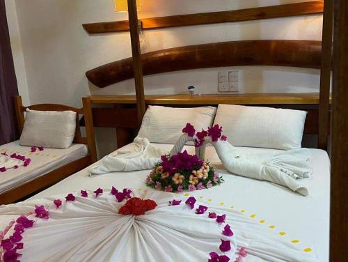 ein Schlafzimmer mit 2 Betten mit Blumen drauf in der Unterkunft RAINIKA VILLA in Thinadhoo