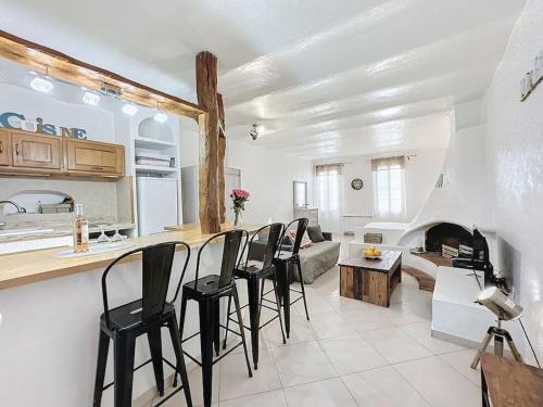 a kitchen and living room with black chairs and a fireplace at Loft Spacieux au Cœur du Village in Vence